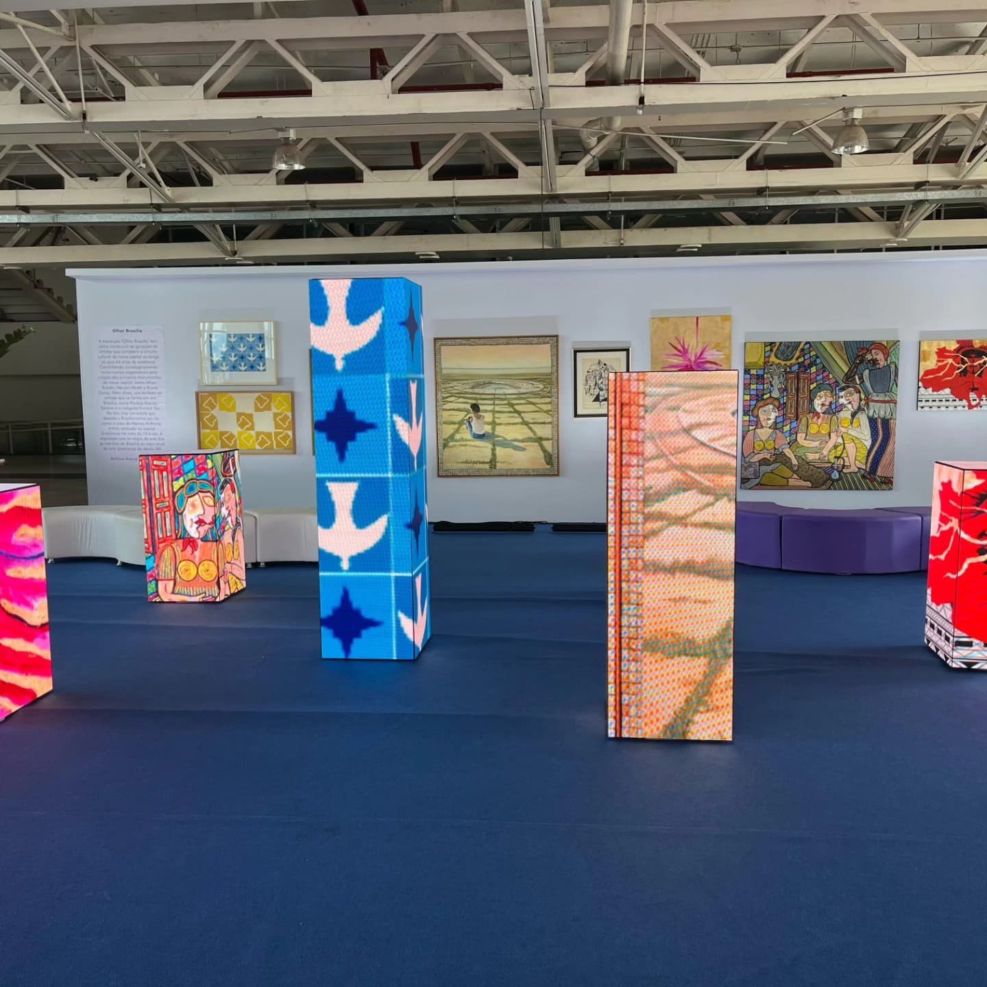 Conjunto de totens de LED em formatos de cubo e coluna em espaço expositivo.